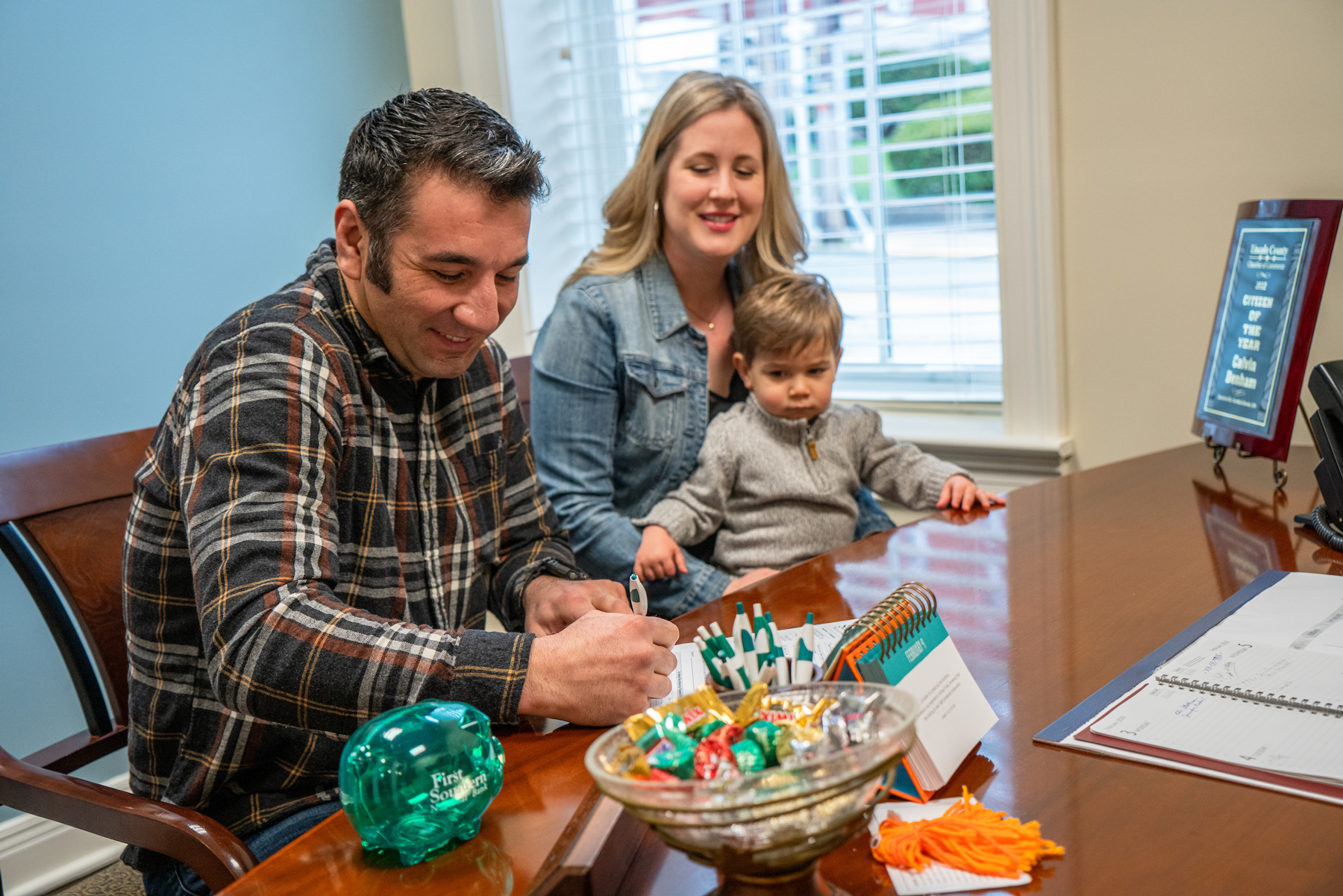 happy family in a banking office signing documents. Digital Marketing, Website Design, Branding, Graphic Design, Logo Design, Advertising, and Marketing Agency services in Danville, Kentucky.